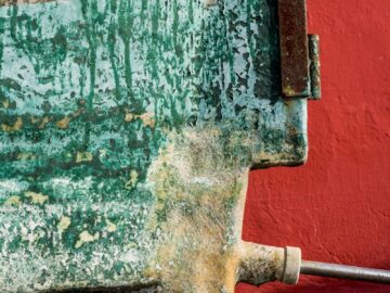 Detailed close-up of a rusty metal object against a vibrant red background.