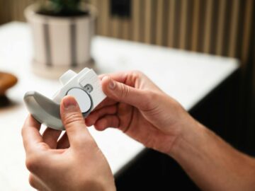 Close-up of hands holding an asthma inhaler, indoors in a modern setting.