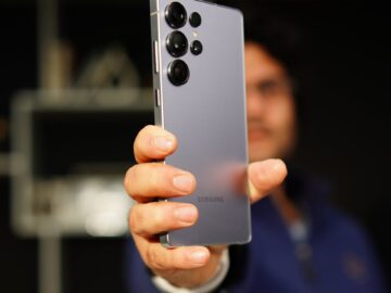 A person holding a Samsung smartphone with focus on the device, indoors.