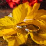 Close-up of wedding rings on vibrant autumn leaves, symbolizing romance and commitment.