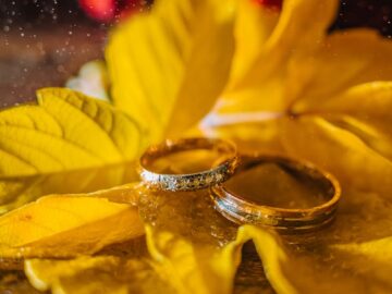 Close-up of wedding rings on vibrant autumn leaves, symbolizing romance and commitment.