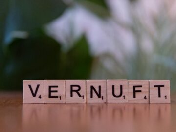 Close-up of Scrabble tiles arranged to spell 'Vernuft' on a wooden surface with blurred background.