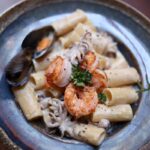 Delicious seafood pasta featuring shrimp, squid, and clams on a rustic plate.