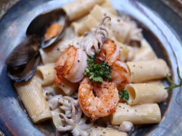 Delicious seafood pasta featuring shrimp, squid, and clams on a rustic plate.
