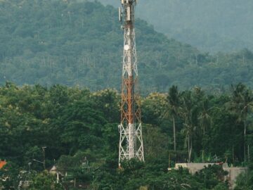Cellular tower surrounded by lush tropical greenery with mountains in the background.