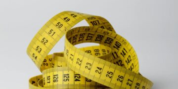 A close-up image of a coiled yellow measuring tape displaying numbers clearly.