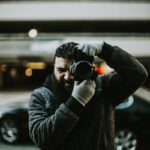 A photographer captured outdoors using a DSLR, showcasing focus and professionalism.