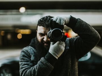 A photographer captured outdoors using a DSLR, showcasing focus and professionalism.