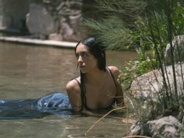 Portrait of a woman in water surrounded by nature, exuding tranquility and elegance.