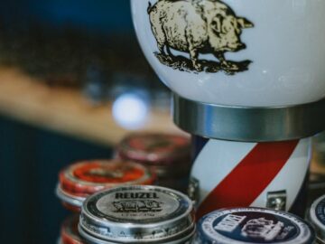 A collection of Reuzel hair products in a stylish barber shop setting with a vintage barber pole lamp.