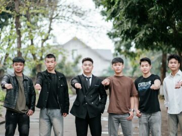 Six young adults standing outdoors, demonstrating unity with outstretched fists.