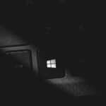 Dramatic black and white close-up of a keyboard's Windows key, featuring stark lighting and shadow.