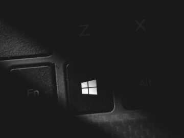 Dramatic black and white close-up of a keyboard's Windows key, featuring stark lighting and shadow.