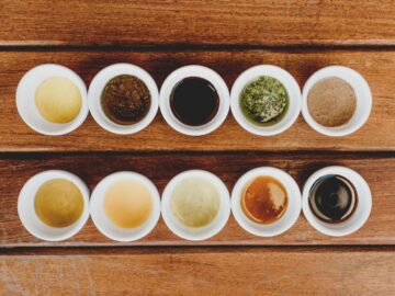 Assorted sauces displayed in bowls on a rustic wooden table.