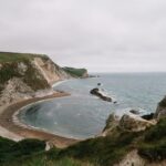 Explore the scenic beauty of Durdle Door's cliffs and beach on a summer day.