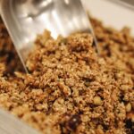 Close-up of crunchy homemade granola being scooped, perfect for a nutritious breakfast.