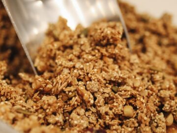 Close-up of crunchy homemade granola being scooped, perfect for a nutritious breakfast.