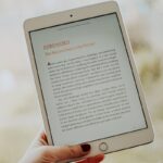 Close-up of a hand holding a tablet displaying an e-book page.