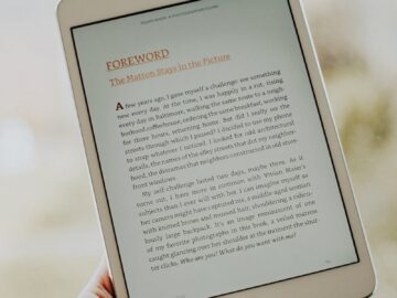 Close-up of a hand holding a tablet displaying an e-book page.