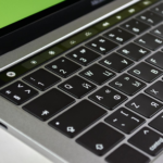 Detailed image of a laptop keyboard featuring Cyrillic characters and a green screen background.