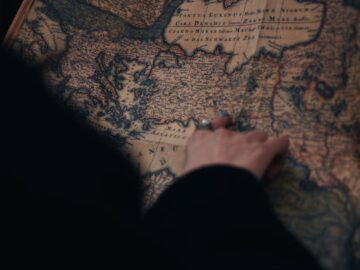 A person examining a detailed vintage map in a dimly lit environment, evoking curiosity and adventure.