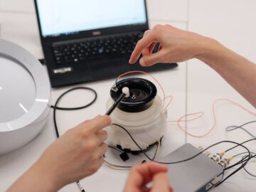 Engineers working on electronic prototype testing with laptop and equipment in a lab.