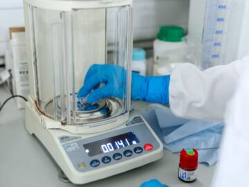 Scientist uses digital scale for precise measurements in a lab setting.
