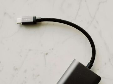 A close-up view of a black USB-C cable with a braided cord resting on a light marble surface.