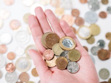 Close-up of a hand holding diverse coins, symbolizing global currency and finance.