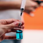 A syringe draws blue liquid from a vial, focusing on precision in healthcare.