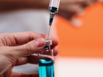 A syringe draws blue liquid from a vial, focusing on precision in healthcare.
