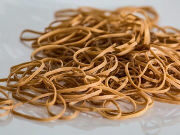 A close-up image of a scattered pile of brown rubber bands on a reflective surface.