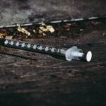 Close-up of a discarded syringe on a rough surface highlighting addiction issues.