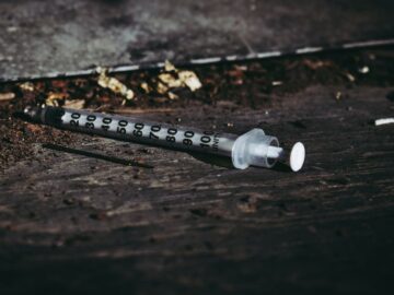 Close-up of a discarded syringe on a rough surface highlighting addiction issues.