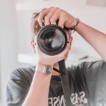 Close-up of a photographer with a camera capturing an image indoors.