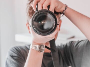 Close-up of a photographer with a camera capturing an image indoors.