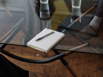 Close-up of a counseling session with two glasses of water and a notepad on a glass table.