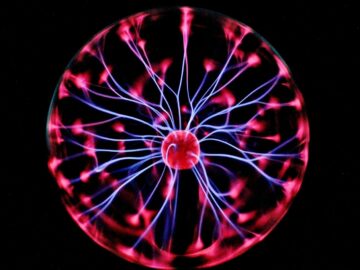 Close-up of a plasma globe with vibrant neon sparks against a dark background.