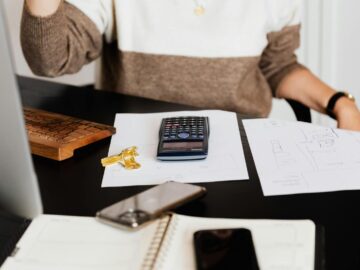 A business desk setup with a calculator, papers, and a keyboard, reflecting a work environment.