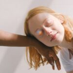 A serene interracial moment with a rainbow reflection adding a magical touch.