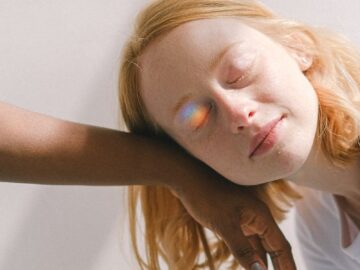 A serene interracial moment with a rainbow reflection adding a magical touch.