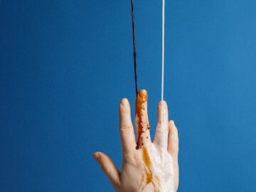 Abstract photo of hands pouring liquids against a blue background.