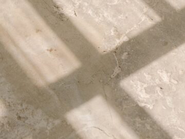 Abstract view of sunlight casting window shadows on a textured concrete surface, creating a grunge aesthetic.