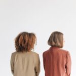 A minimalist portrait of two women standing back to back, showcasing unity and diversity.