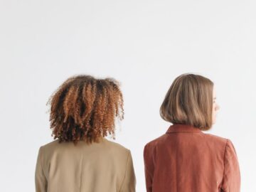 A minimalist portrait of two women standing back to back, showcasing unity and diversity.