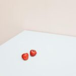 A clean and minimalist shot of two fresh strawberries on a white table.