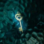 A golden heart-shaped key resting on a teal textured surface, offering a unique contrast.