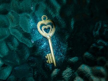 A golden heart-shaped key resting on a teal textured surface, offering a unique contrast.