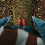 High angle view of brown shoes standing on a moss-covered log in a forest, perfect for adventure themes.