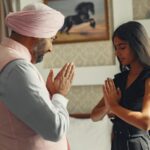 A Sikh father and daughter share a moment of meditation and cultural practice indoors.